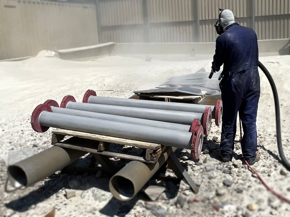 Person sandblasting or painting parts at facility